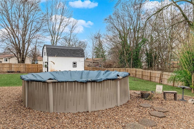 view of yard featuring a fenced backyard, a shed, a fenced in pool, and an outbuilding