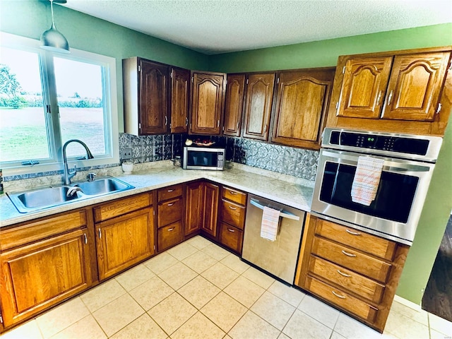 kitchen featuring light tile patterned flooring, stainless steel appliances, a sink, light countertops, and decorative backsplash