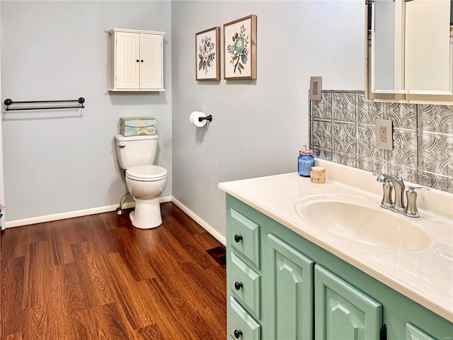 bathroom with toilet, baseboards, wood finished floors, and vanity