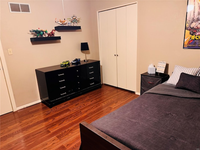 bedroom featuring dark wood-type flooring, a closet, visible vents, and baseboards