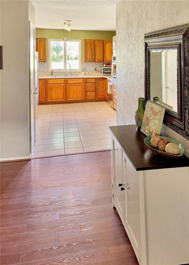 kitchen featuring brown cabinetry, backsplash, and light wood-style floors