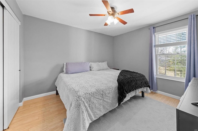 bedroom with a ceiling fan, baseboards, light wood-type flooring, and a closet