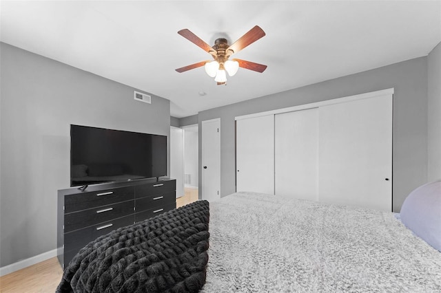 bedroom featuring visible vents, baseboards, light wood-type flooring, a closet, and a ceiling fan