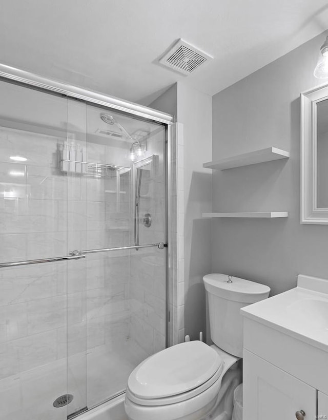 bathroom with vanity, toilet, visible vents, and a stall shower