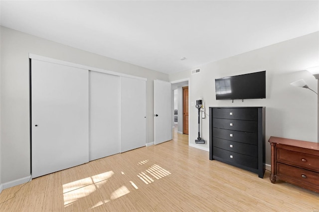 unfurnished bedroom featuring visible vents, baseboards, a closet, and light wood finished floors