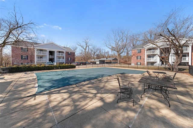 community pool with a patio and fence