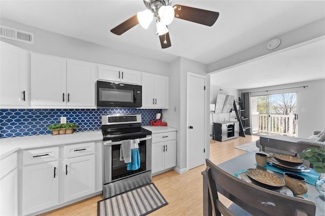 kitchen featuring visible vents, light wood-style flooring, electric stove, black microwave, and light countertops