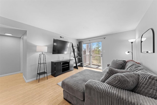 living area featuring visible vents, baseboards, and wood finished floors