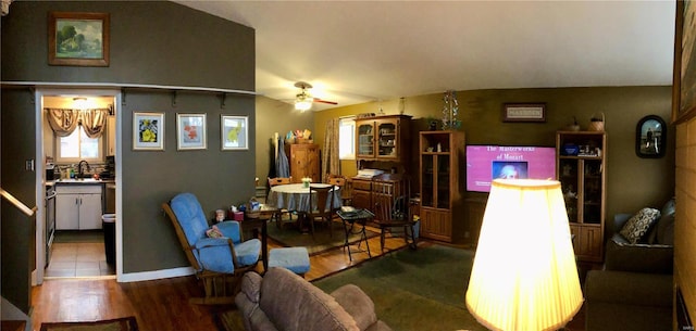 living room featuring ceiling fan, baseboards, and wood finished floors