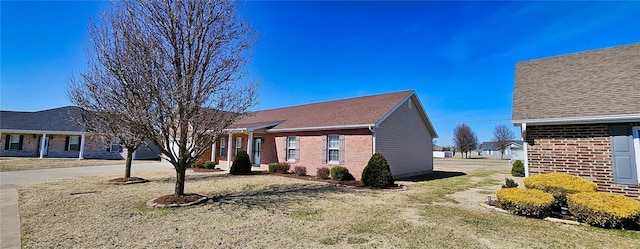 view of front facade with a front yard, brick siding, and driveway