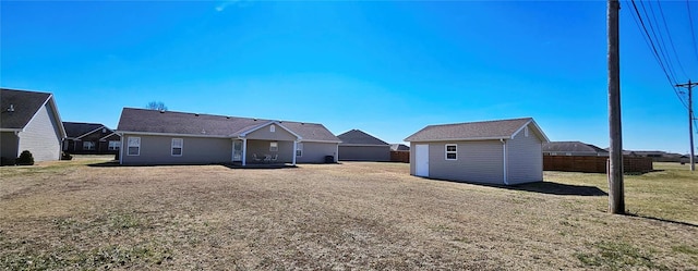 rear view of property with a storage shed, a lawn, an outdoor structure, and fence