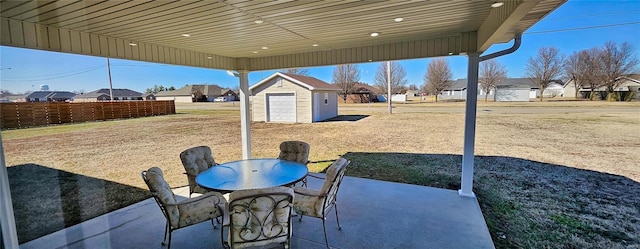 view of patio / terrace with a residential view, fence, a storage unit, outdoor dining area, and an outdoor structure