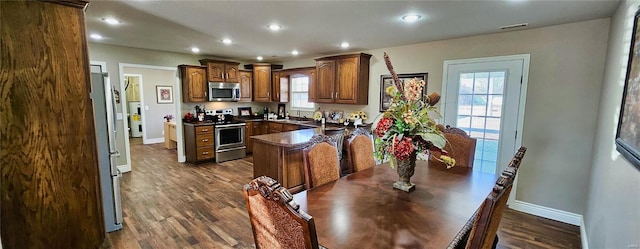 kitchen featuring appliances with stainless steel finishes, dark wood-type flooring, dark countertops, and recessed lighting