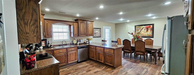 kitchen featuring dark wood-style floors, a peninsula, stainless steel appliances, a sink, and recessed lighting