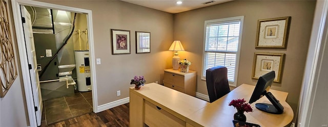 office space with electric water heater, dark wood finished floors, visible vents, and baseboards