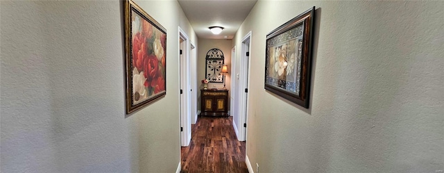 hallway featuring dark wood finished floors and a textured wall