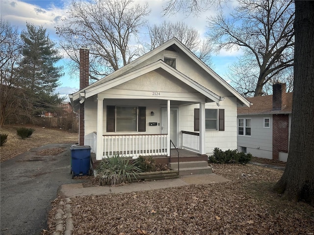 bungalow-style home featuring covered porch and a chimney