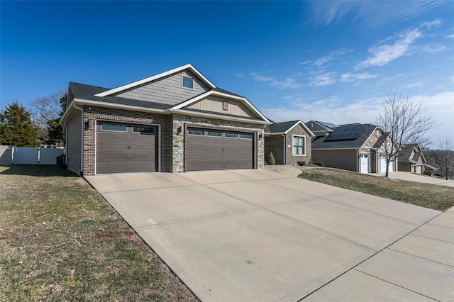 craftsman house with a garage, fence, driveway, stone siding, and a front lawn