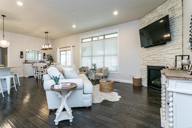 living area featuring a stone fireplace, recessed lighting, dark wood finished floors, and baseboards