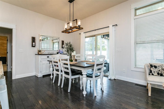 dining room featuring dark wood-style floors, visible vents, baseboards, and an inviting chandelier