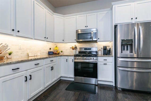 kitchen featuring dark wood-style floors, backsplash, appliances with stainless steel finishes, white cabinetry, and light stone countertops