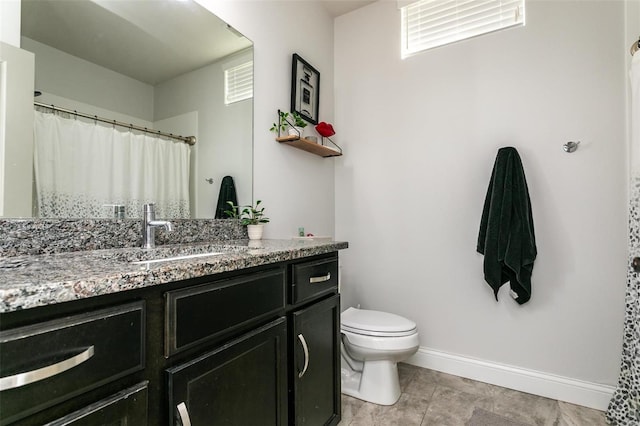 bathroom featuring baseboards, vanity, and toilet