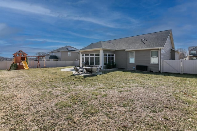 rear view of house featuring a sunroom, a yard, a fenced backyard, and a gate