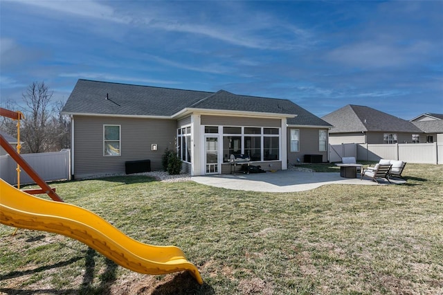 rear view of property with a patio, a playground, a fenced backyard, a sunroom, and a yard