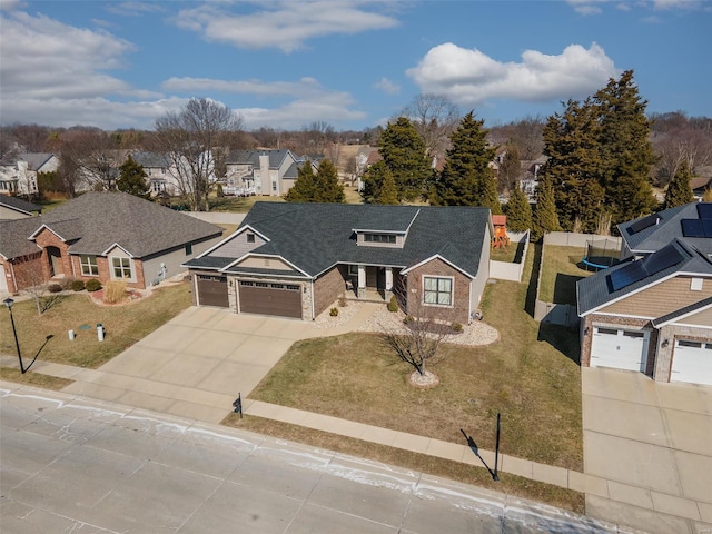 view of front facade with an attached garage, a residential view, concrete driveway, and a front yard