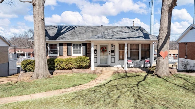 view of front facade with a front yard, a porch, and brick siding