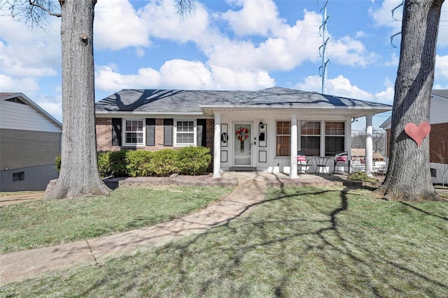 view of front of property featuring brick siding, covered porch, and a front lawn