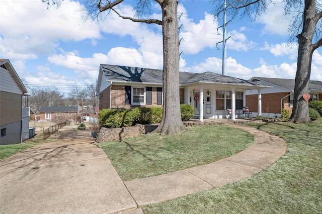 view of front of property with brick siding, covered porch, and a front yard