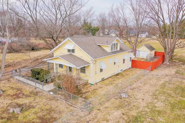 view of front of property featuring covered porch, a shingled roof, and fence private yard