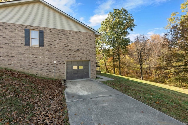 view of home's exterior with brick siding, a lawn, driveway, and a garage