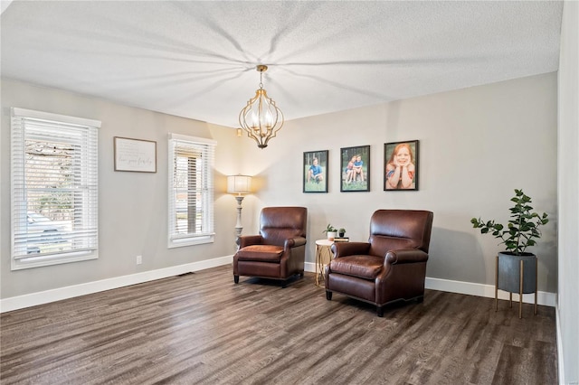 living area with a notable chandelier, baseboards, dark wood-type flooring, and a textured ceiling