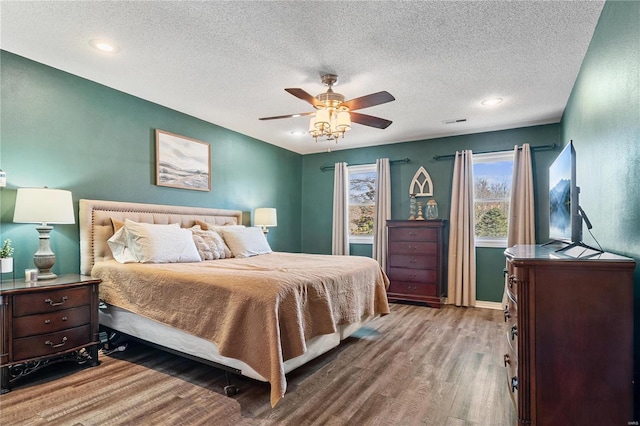 bedroom featuring a ceiling fan, wood finished floors, baseboards, and a textured ceiling