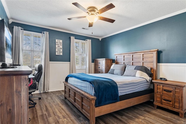 bedroom featuring visible vents, a textured ceiling, wood finished floors, and wainscoting