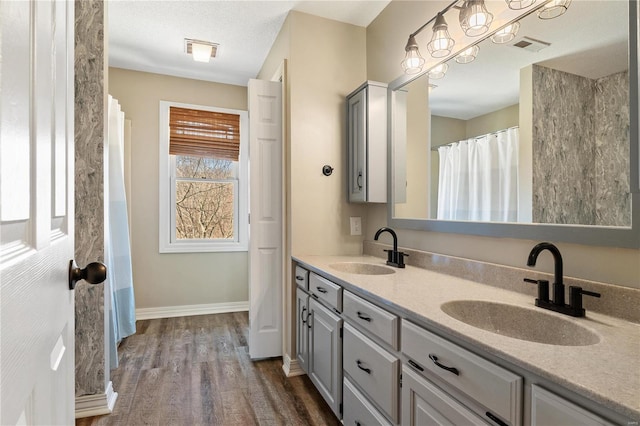 bathroom featuring a sink, baseboards, wood finished floors, and double vanity