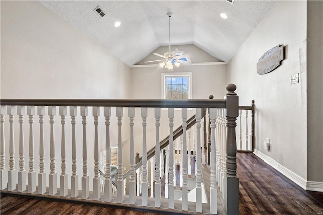 hall featuring wood finished floors, visible vents, baseboards, vaulted ceiling, and an upstairs landing