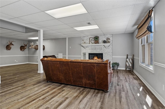 living room with visible vents, a drop ceiling, wood finished floors, a fireplace, and baseboards