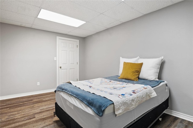 bedroom featuring wood finished floors, baseboards, and a paneled ceiling