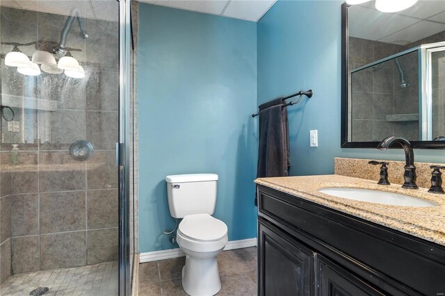 full bathroom featuring vanity, baseboards, a stall shower, tile patterned flooring, and toilet