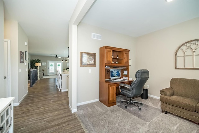 office featuring dark wood-type flooring, visible vents, baseboards, and a ceiling fan