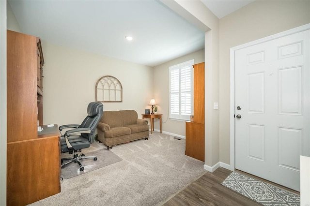 carpeted office space featuring wood finished floors and baseboards