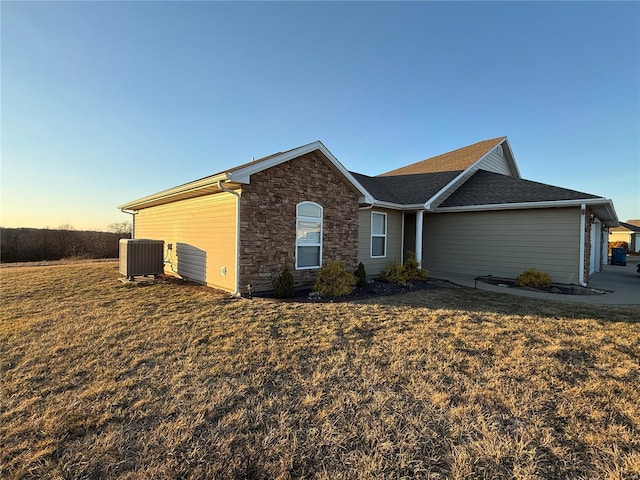 single story home featuring stone siding, a front lawn, and central AC unit