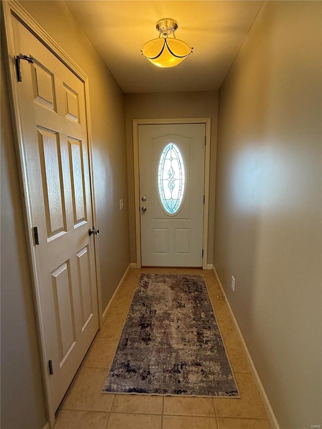 doorway to outside with light tile patterned flooring and baseboards