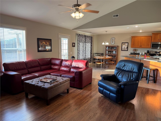 living area with lofted ceiling, visible vents, plenty of natural light, and wood finished floors