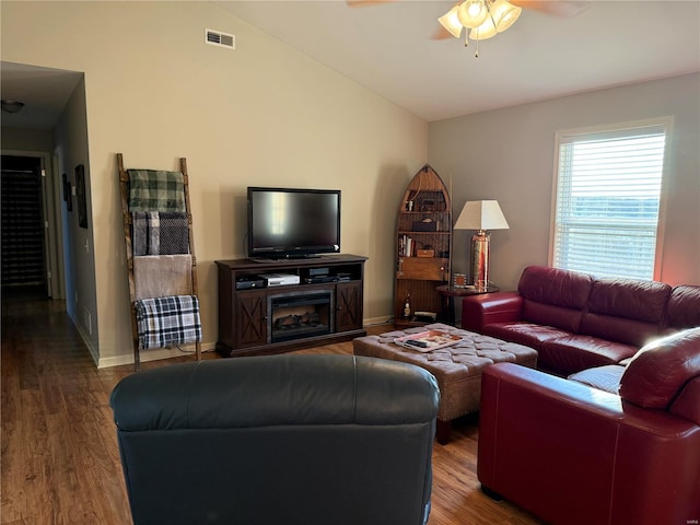 living area with lofted ceiling, visible vents, a ceiling fan, wood finished floors, and baseboards