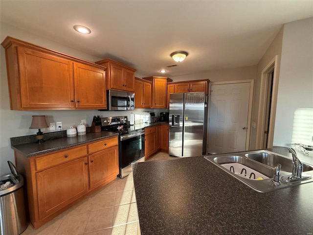 kitchen with light tile patterned floors, brown cabinetry, dark countertops, stainless steel appliances, and a sink