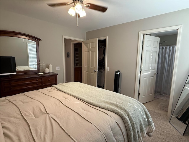 bedroom with a ceiling fan, light colored carpet, and connected bathroom